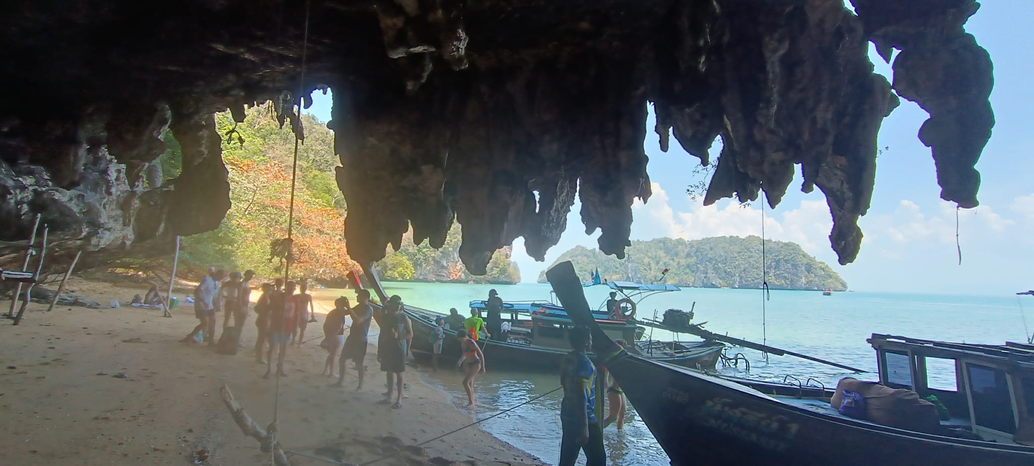 Bateaux traditionnels sur une plage sous une grotte calcaire en Thaïlande
